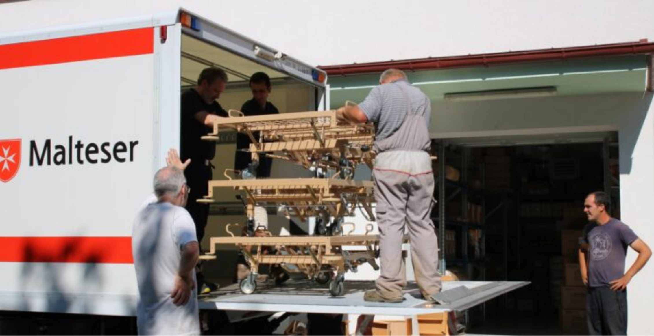 Volonteri istovaruju bolničke krevete iz kamiona s oznakom Malteškog reda u sklopu donacije Hrvatskom Caritasu